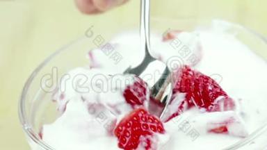 男人用<strong>勺子</strong>在透明的杯子<strong>里</strong>吃健康的草莓，配上白色酸奶，健康<strong>水果</strong>的概念